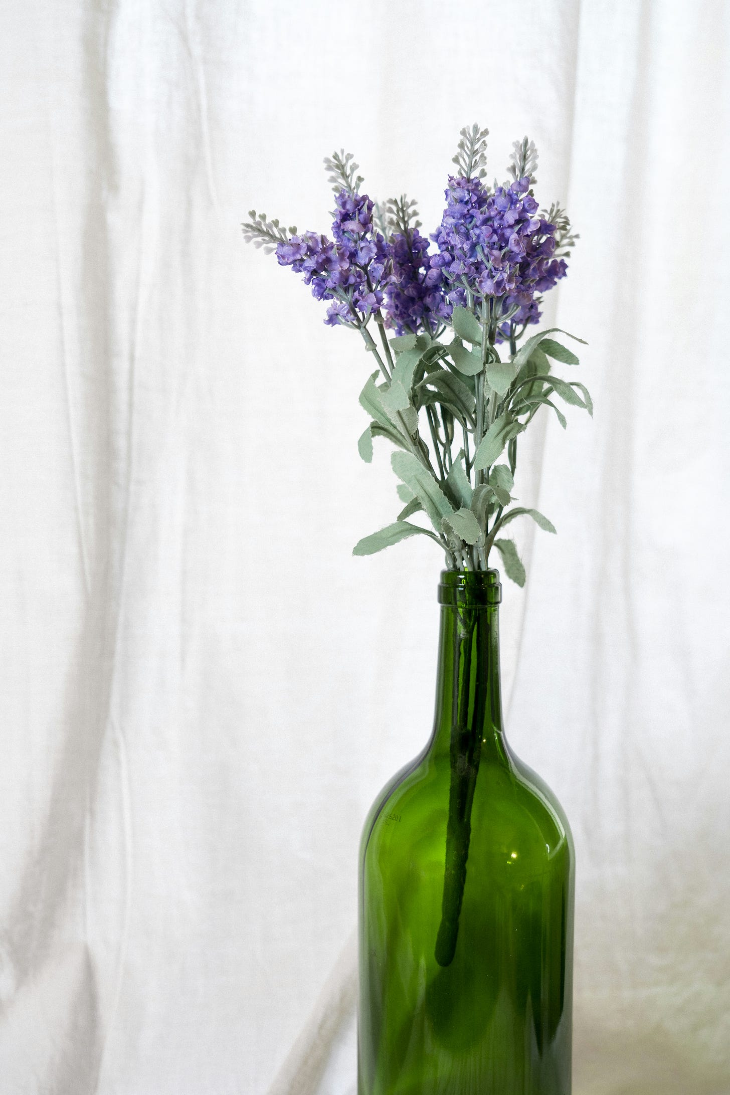 Hyacinths are held as a bunch in a bottle of wine.