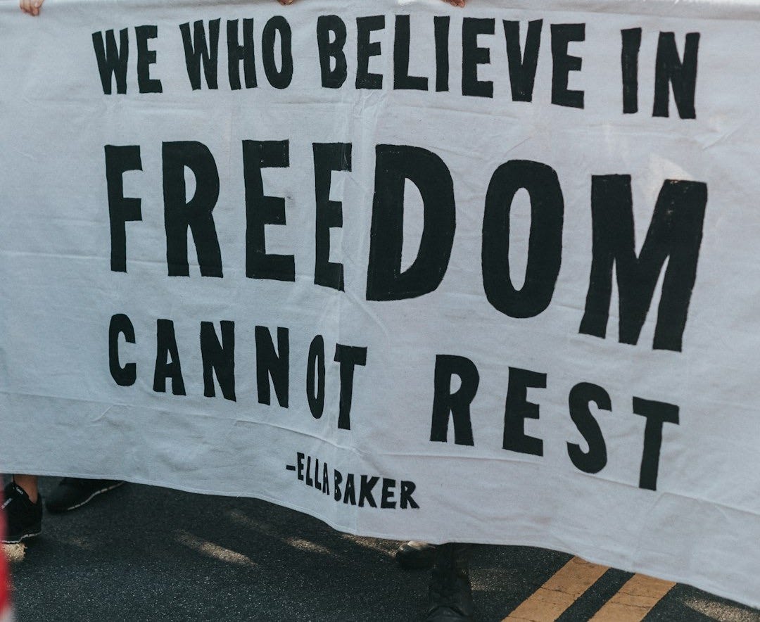 a group of protesters holding a sign that says we who believe in freedom cannot rest