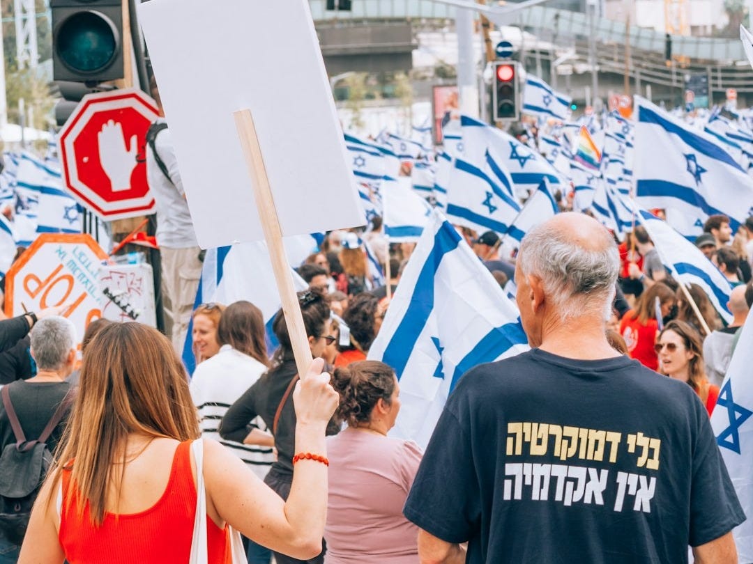 a group of people walking down a street holding signs a group of people walking down a street holding signs