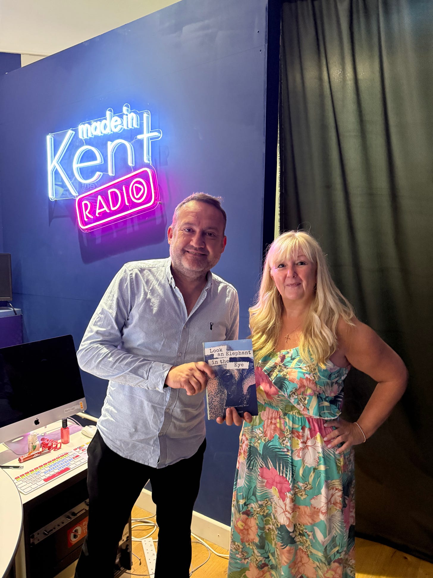 me holding a copy of one of my books in the made in kent radio station, with the presenter and DJ next to me