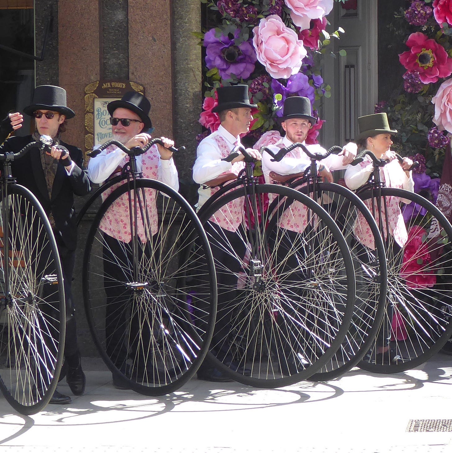 High-wheeler riders wearing flowery shirts, standing outside a pub with their bicycles. High-wheeler riders wearing flowery shirts, standing outside a pub with their bicycles.