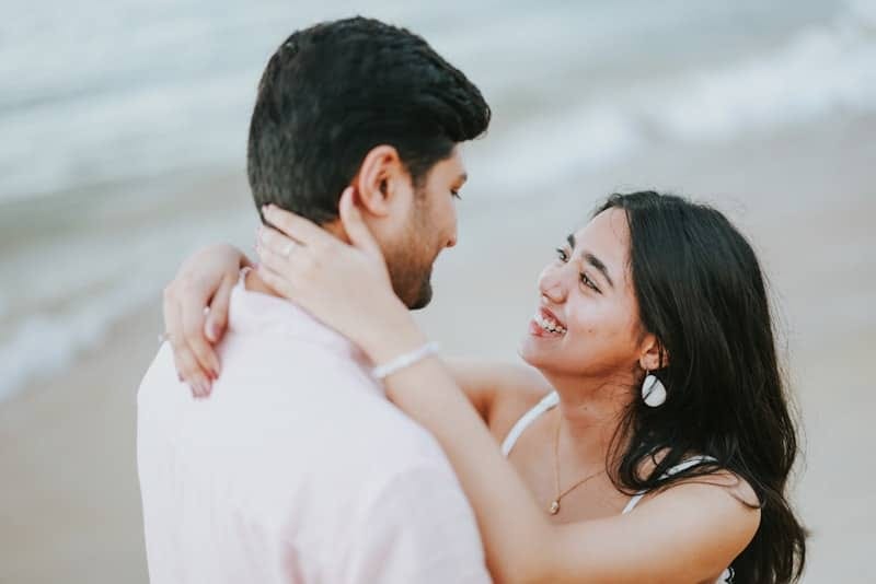 Couple embracing on a beach with ocean background