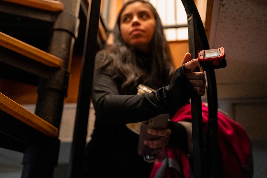 Tiffany Patino wears a pulse oximeter to monitor her vitals as she walks up the stairs in her home.