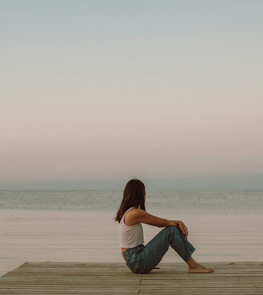 woman in black dress standing on beach during daytime