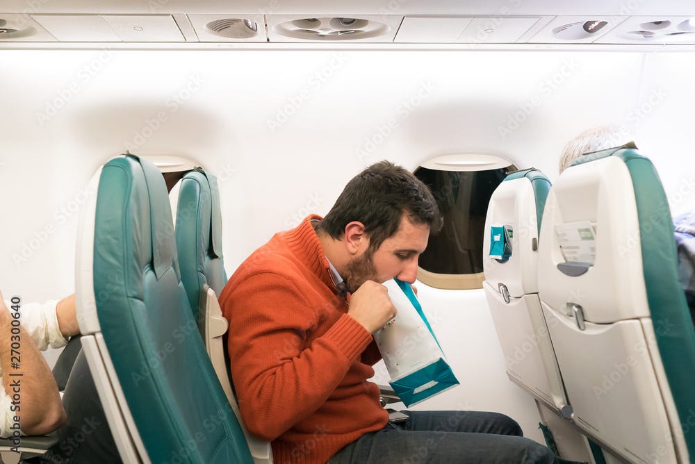 Airsickness. Man feels very bad on the air plane, using a sickness bag  (also known as a sick sack, emesis bag, barf bag, vomit bag) Stock Photo |  Adobe Stock