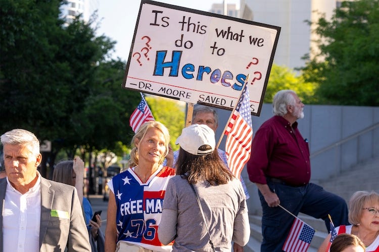 (Rick Egan | The Salt Lake Tribune)  Supporters of Kirk Moore rally on the steps of the Orrin G. Hatch Federal Courthouse in Salt Lake City on Monday, July 7, 2025. Moore is accused of fraudulently distributing COVID-19 vaccination cards.