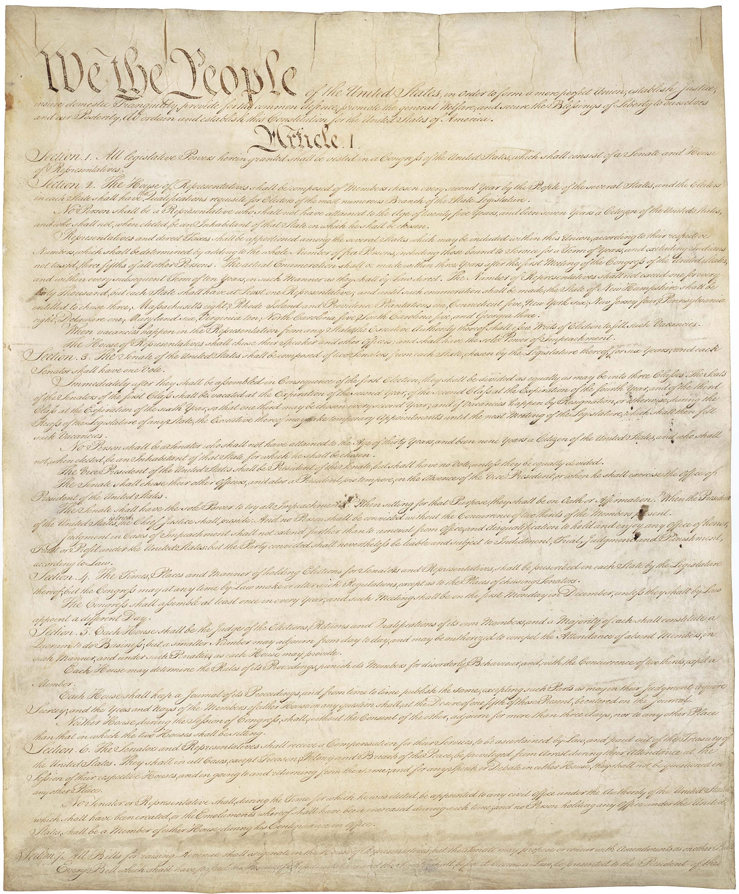 The image shows the original handwritten first page of the United States Constitution. At the top, the large, ornate words "We the People" are prominently visible, followed by the preamble in elegant script. Below, "Article I" is clearly labeled, with several sections detailed in smaller cursive writing. The parchment appears aged and slightly stained, with a generally yellowish hue. The document is a foundational legal and historical text, authored in 1787, and is a recognizable symbol of American governance and history. No modern brands or landmarks are visible.