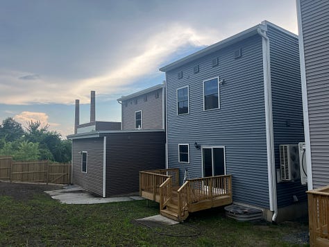 Exterior photos of new townhouses from the street and from the backyard. Several interior photos of a first floor with an open layout.