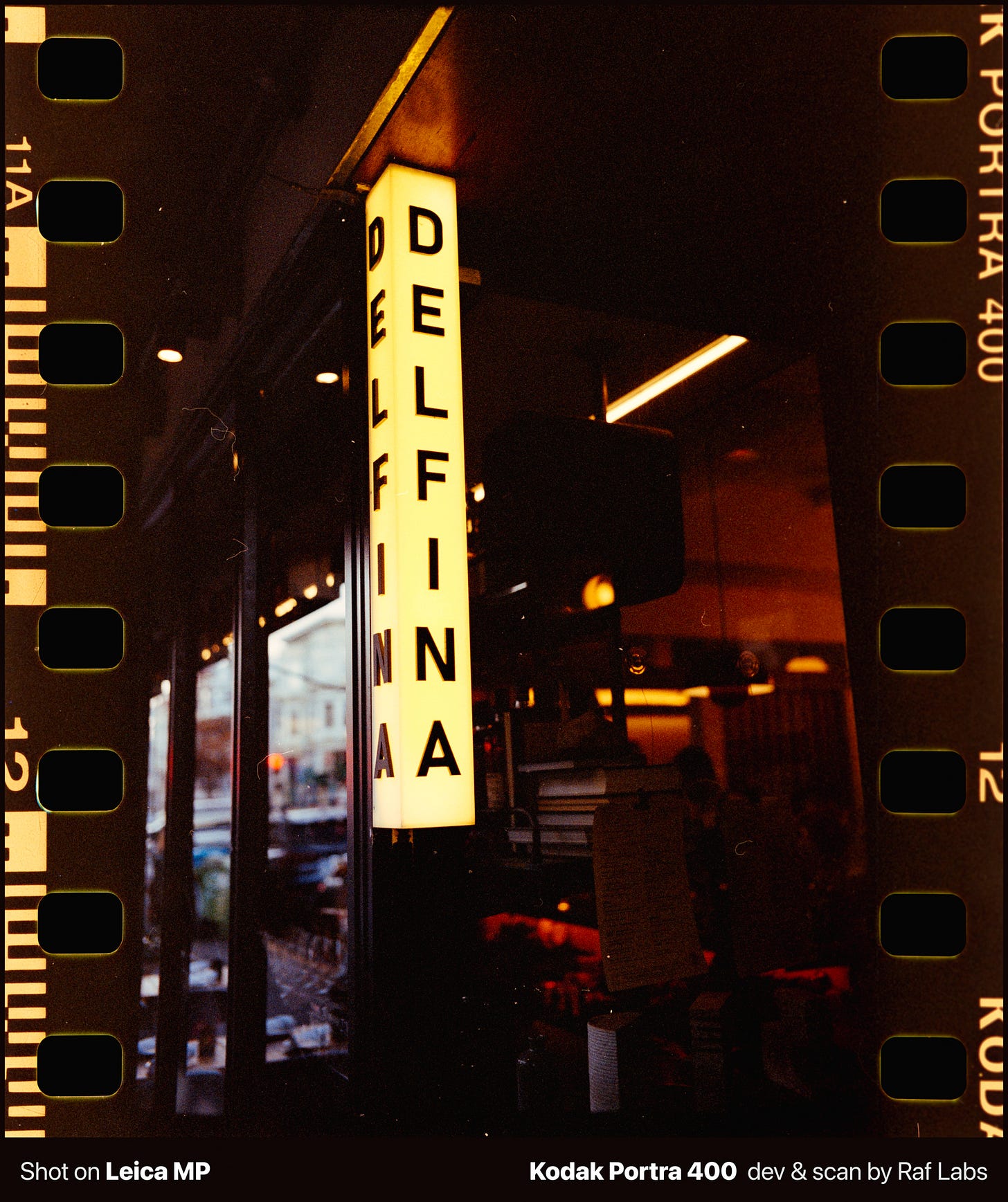 Illuminated Delfina restaurant sign at night in San Francisco, vintage film photography aesthetic