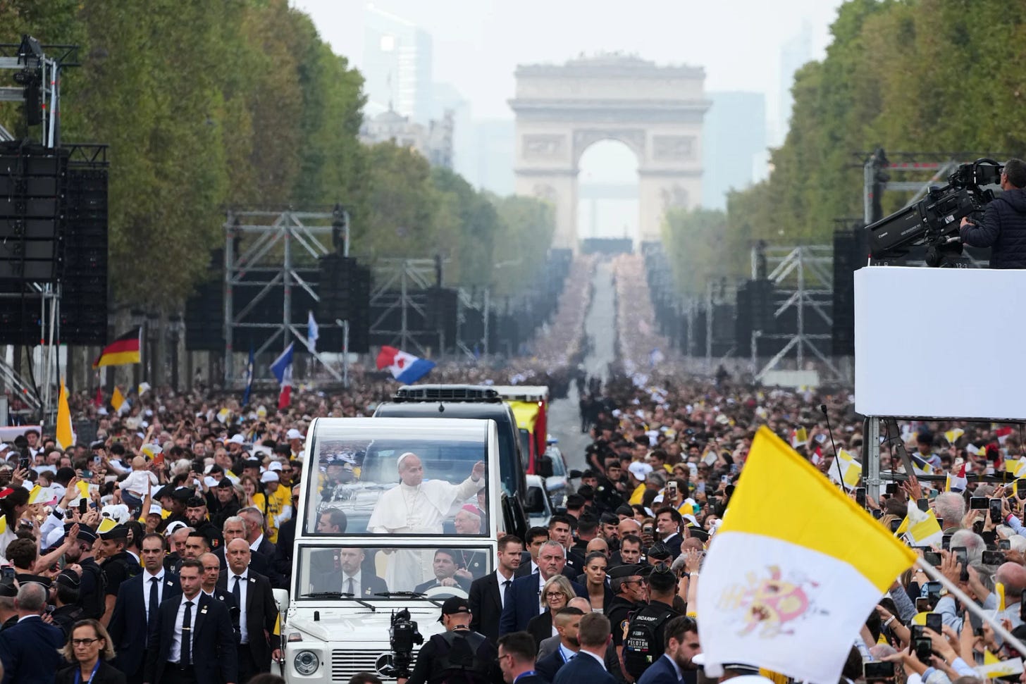 Pope Leo XIV waves from the popemobile on the Champs-Élysées with the Arc de Triomphe behind him Pope Leo XIV waves from the popemobile on the Champs-Élysées with the Arc de Triomphe behind him