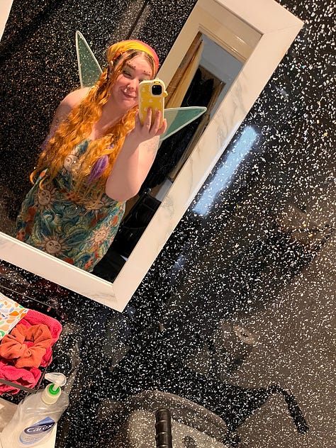 photo 1: A wide landscape view of a large grassy park with tall trees silhouetted against dramatic cloud formations and bright sunlight breaking through the sky.  photo 2: A mirror selfie of a person dressed in a colourful fairy outfit, wearing a patterned dress, a bright headscarf, green eye makeup, and translucent fairy wings. They are smiling and holding their phone in a bathroom with black speckled walls.  photo 3: A candid photo of the same person sitting in the front seat of a car, laughing with their eyes closed. They have long orange hair with purple ends, star stickers above their eyebrows, green eye makeup, and a patterned dress with thin straps.