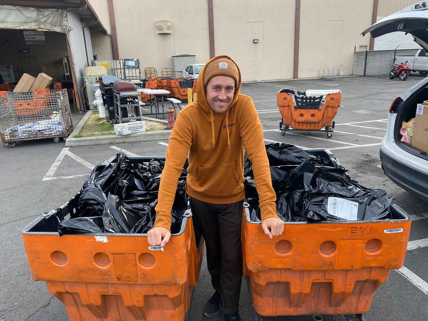 Image of a man standing between two carts filled with pickleball paddle shipments