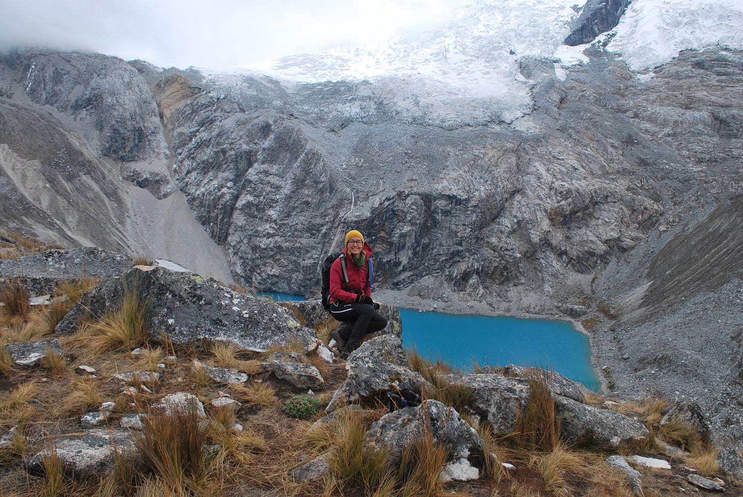 The photograph shows the writer, a white woman, sitting in front of a mountain lake. In the back, the Peruvian Andes are visible. 