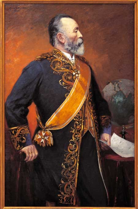 An oil portrait of Heinrich von Stephan in profile — gray-bearded, in a dark, heavily gold-embroidered uniform with a wide yellow sash and a hanging cross. One hand rests at his side, the other holds a paper beside a desk with a globe, against a reddish-brown background. An oil portrait of Heinrich von Stephan in profile — gray-bearded, in a dark, heavily gold-embroidered uniform with a wide yellow sash and a hanging cross. One hand rests at his side, the other holds a paper beside a desk with a globe, against a reddish-brown background.