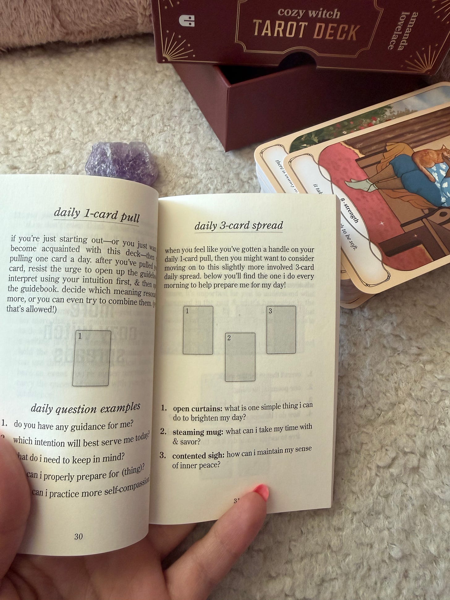 Open guidebook showing a daily 3-card tarot spread layout Open guidebook showing a daily 3-card tarot spread layout