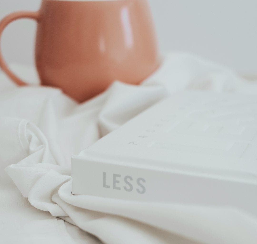 a coffee mug sitting on top of a bed next to a book a coffee mug sitting on top of a bed next to a book