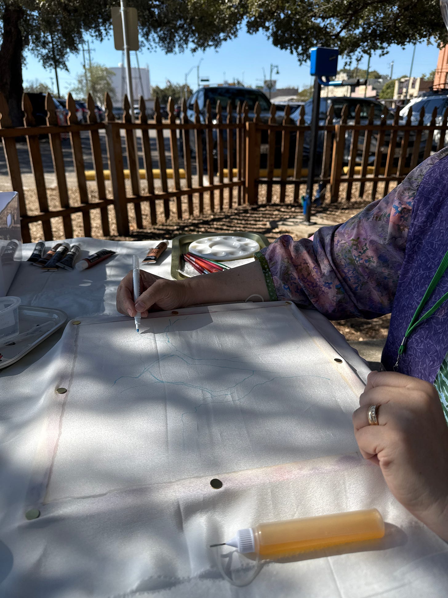 Artist Gwendolyn Hustvedt painting at outdoor festival booth in Buda Texas