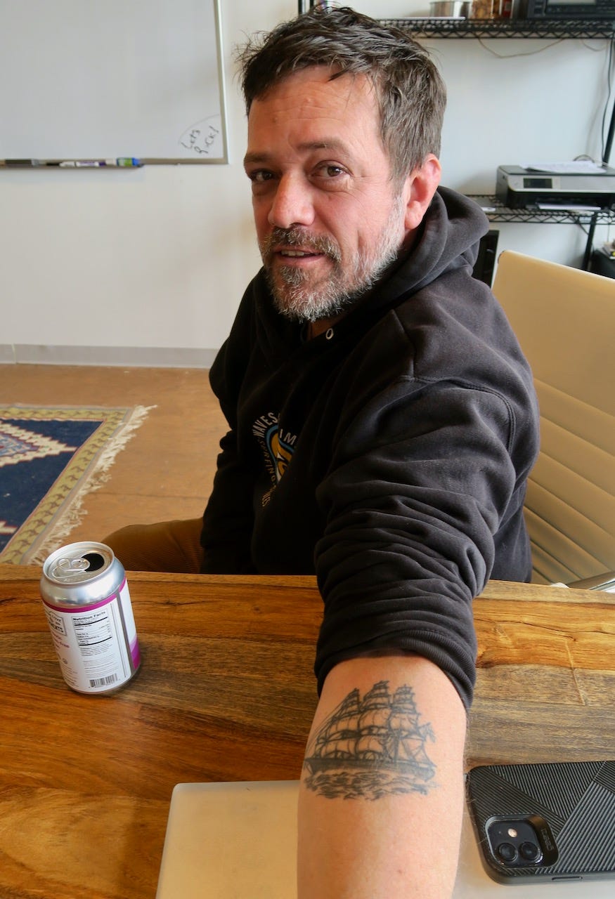 A person sitting at a table with a tattoo on his arm

Description automatically generated