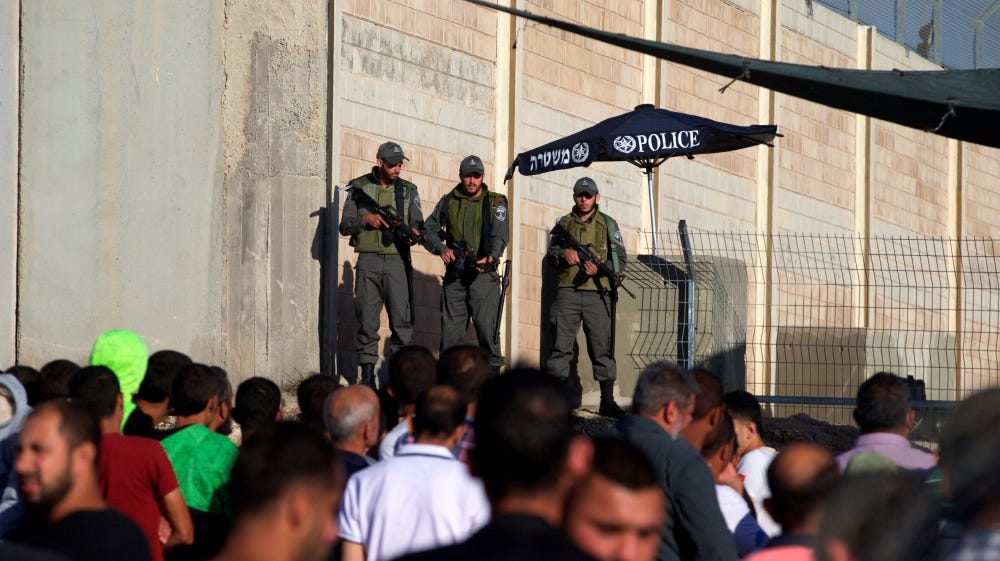 Palestinians wait to cross the Qalandia military checkpoint in the occupied West Bank as Israeli officers stand guard, in 2016 [Reuters]
