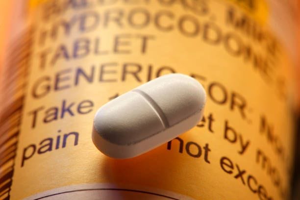 Opioid Pill On A Hydrocodone Prescription Pill Bottle A close up of a single opioid pill resting on top of a prescription pill bottle. vicodin stock pictures, royalty-free photos & images