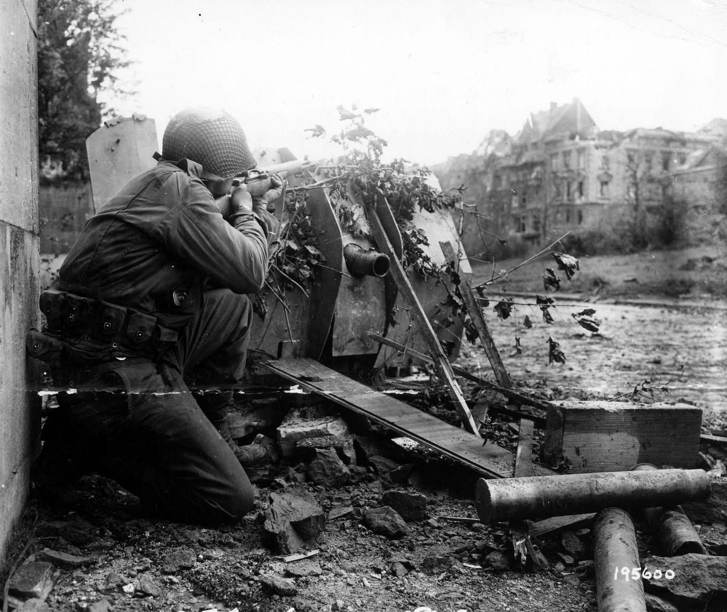 Pvt. William Zukerbrow, 1st Infantry Division, Brooklyn, N.Y., skillfully draws a bead on a Nazi sniper from the cover of a knocked-out German anti-tank gun in Aachen, Germany, October 29, 1944.