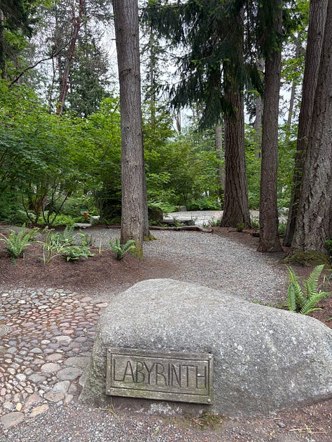 forest setting with labyrinth, brass prayer wheel, and bridge made from a tree