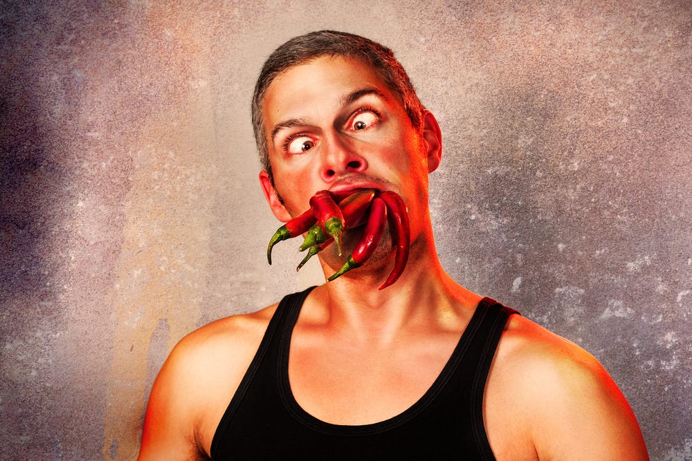 ridiculous expression of a man with lots of hot chillies in his mouth ridiculous expression of a man with lots of hot chillies in his mouth