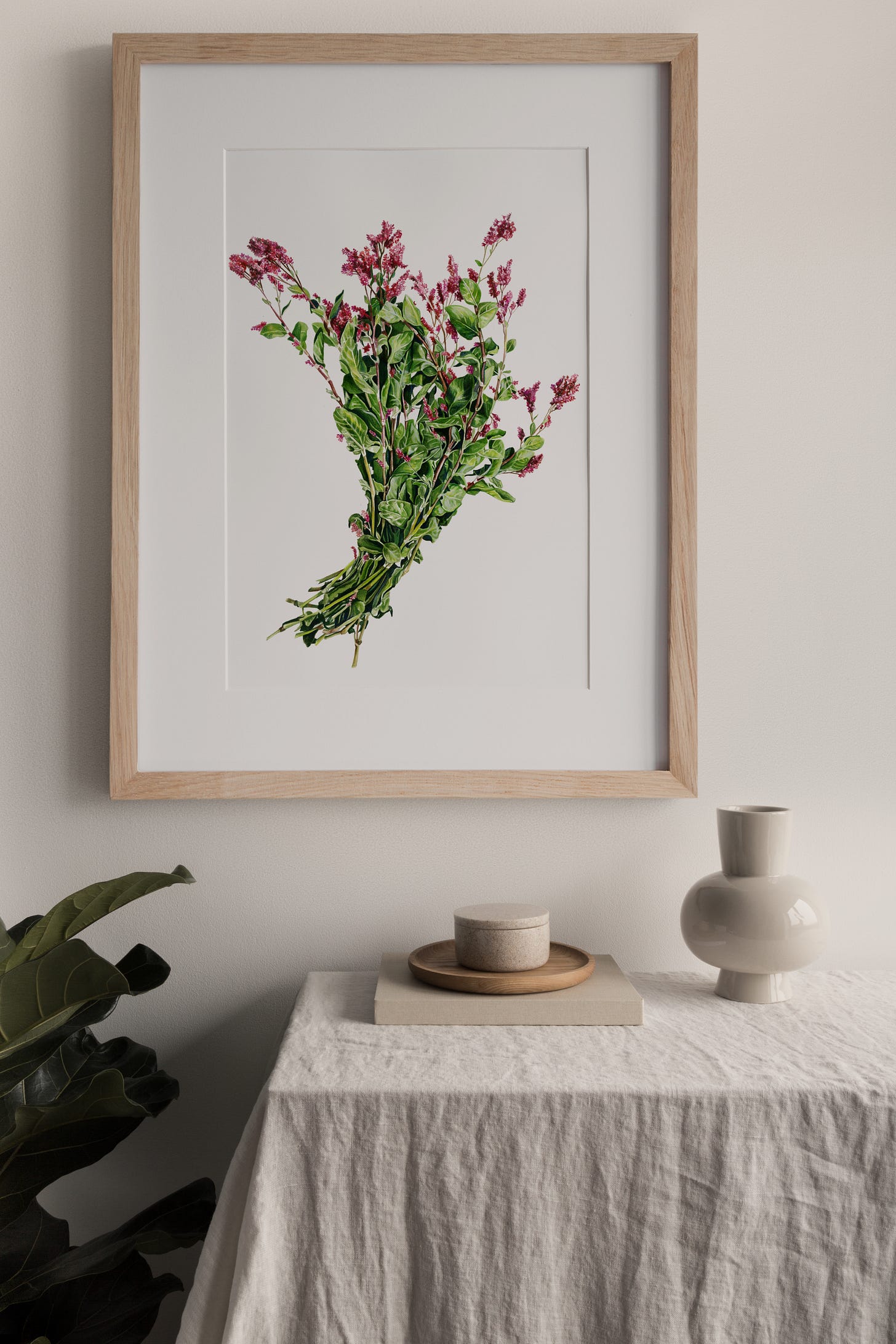 A framed finished indigo painting on the wall with a table below it. 