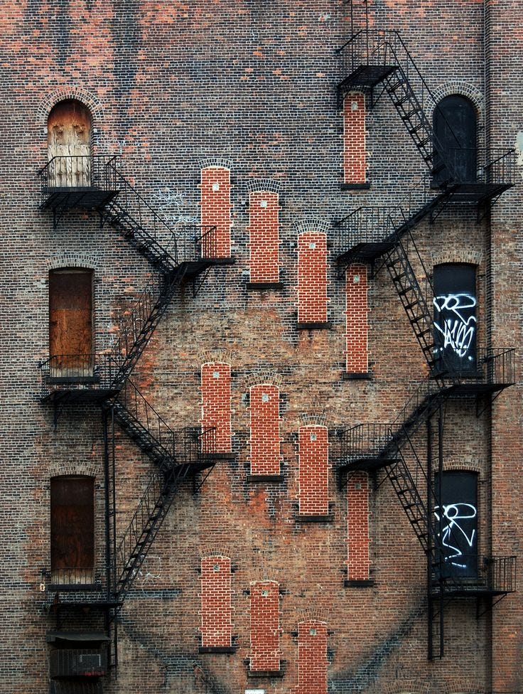 This may contain: an old brick building with lots of windows and graffiti on the side, as seen from above