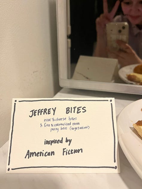 A bowl of pasta salad labeled "Pasta Chives", a Miller High Life for The Holdovers, two tall boys labeled "Anatomy of a Tall Boy," a sign reading "Jeffrey Bites - mac & cheese bites and caramelized onion & feta bites."