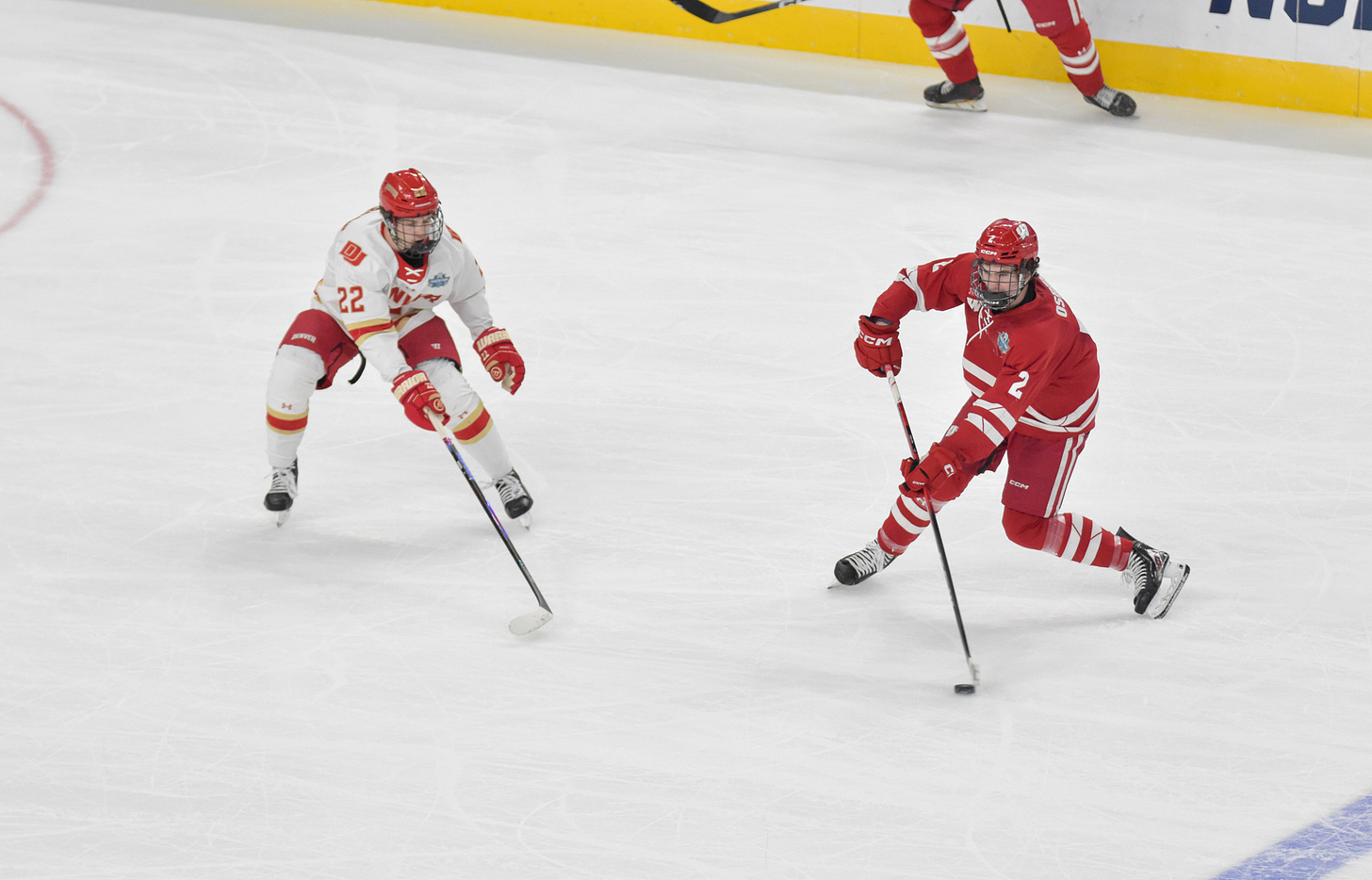 Wisconsin sophomore and Buffalo Sabres draft pick Luke Osburn looks across ice for teammate to pass to while being defended in NCAA national championship game.