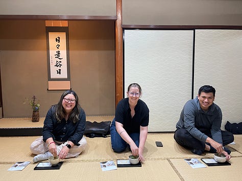 A collage of nine photos from travels in Japan: two sumo wrestlers posing with visitors; vintage kabuki posters on display; a small group sitting on tatami mats during a cultural workshop; a mannequin dressed in a traditional kimono with floral patterns; three people smiling in front of a lantern-filled temple gate; a night market vendor grilling skewers and takoyaki; two friends taking a selfie in Shibuya among bright city signs; the waterfront skyline and Ferris wheel in Yokohama; and a narrow alleyway in Kyoto lined with glowing izakaya lanterns.