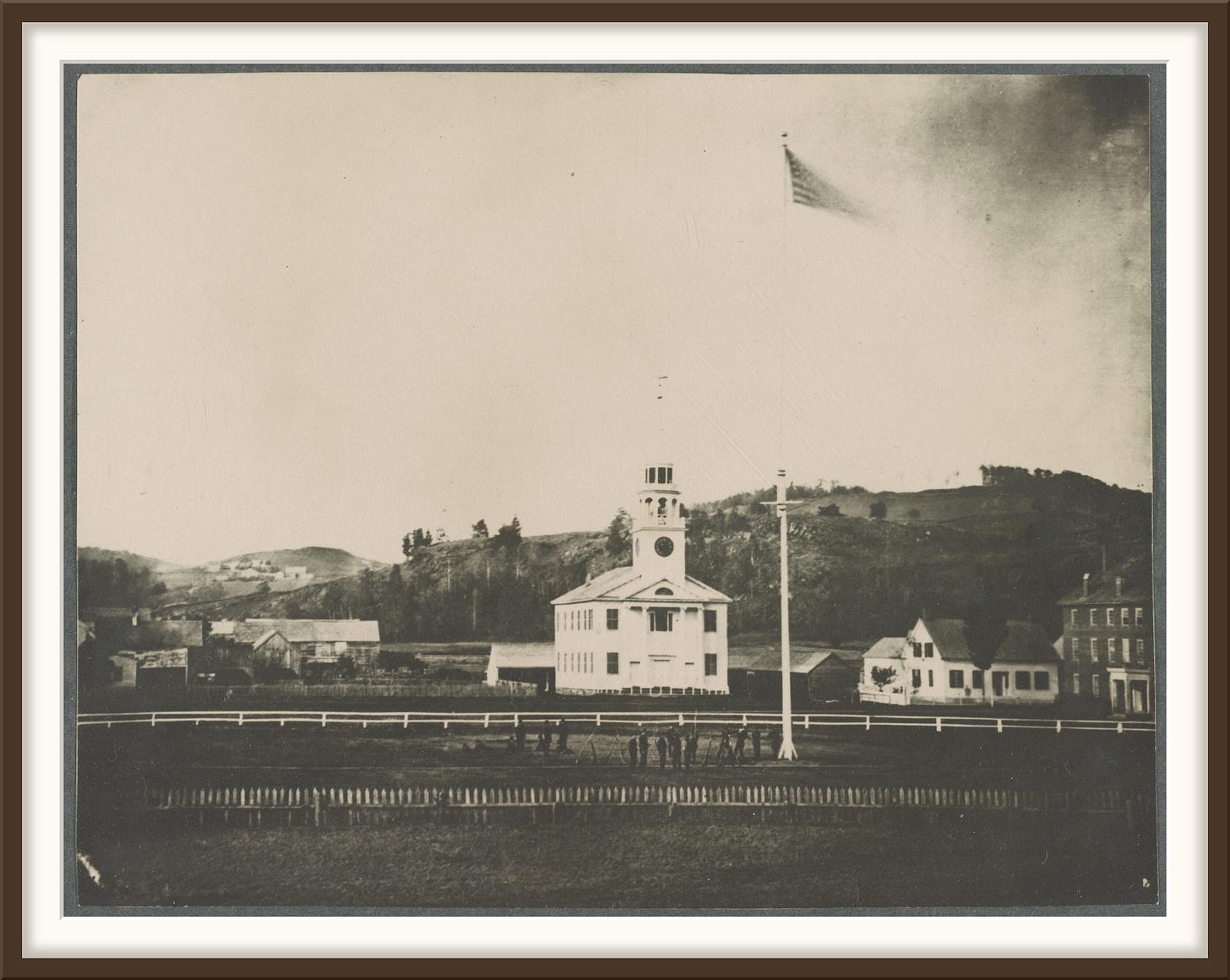 A house up on timbers in the middle of Central Street, a horse walking a circle at a capstan