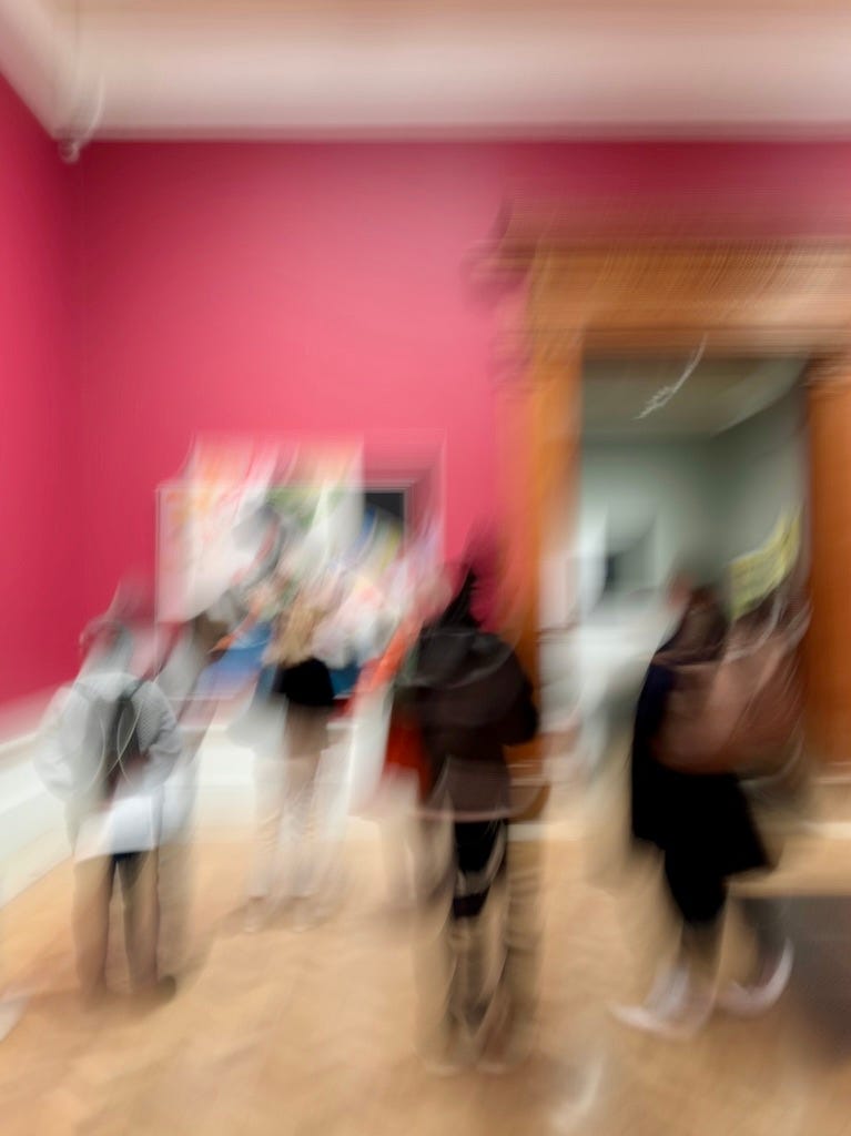A blurry long exposure photo people in a gallery looking at art. The gallery has cherry red walls. A blurry long exposure photo people in a gallery looking at art. The gallery has cherry red walls.