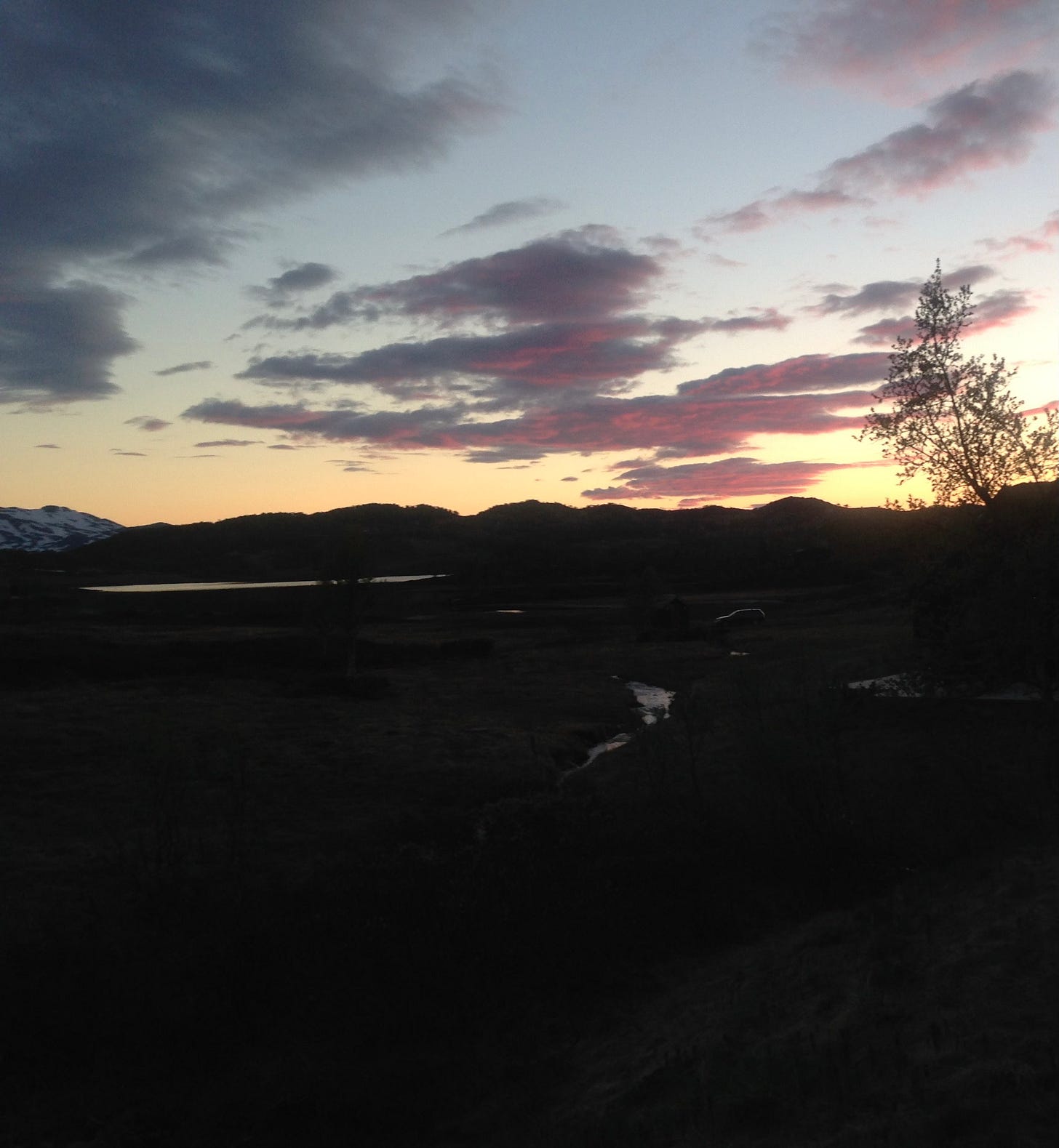 Early pink cloud morning with dark foreground of hills and streams.