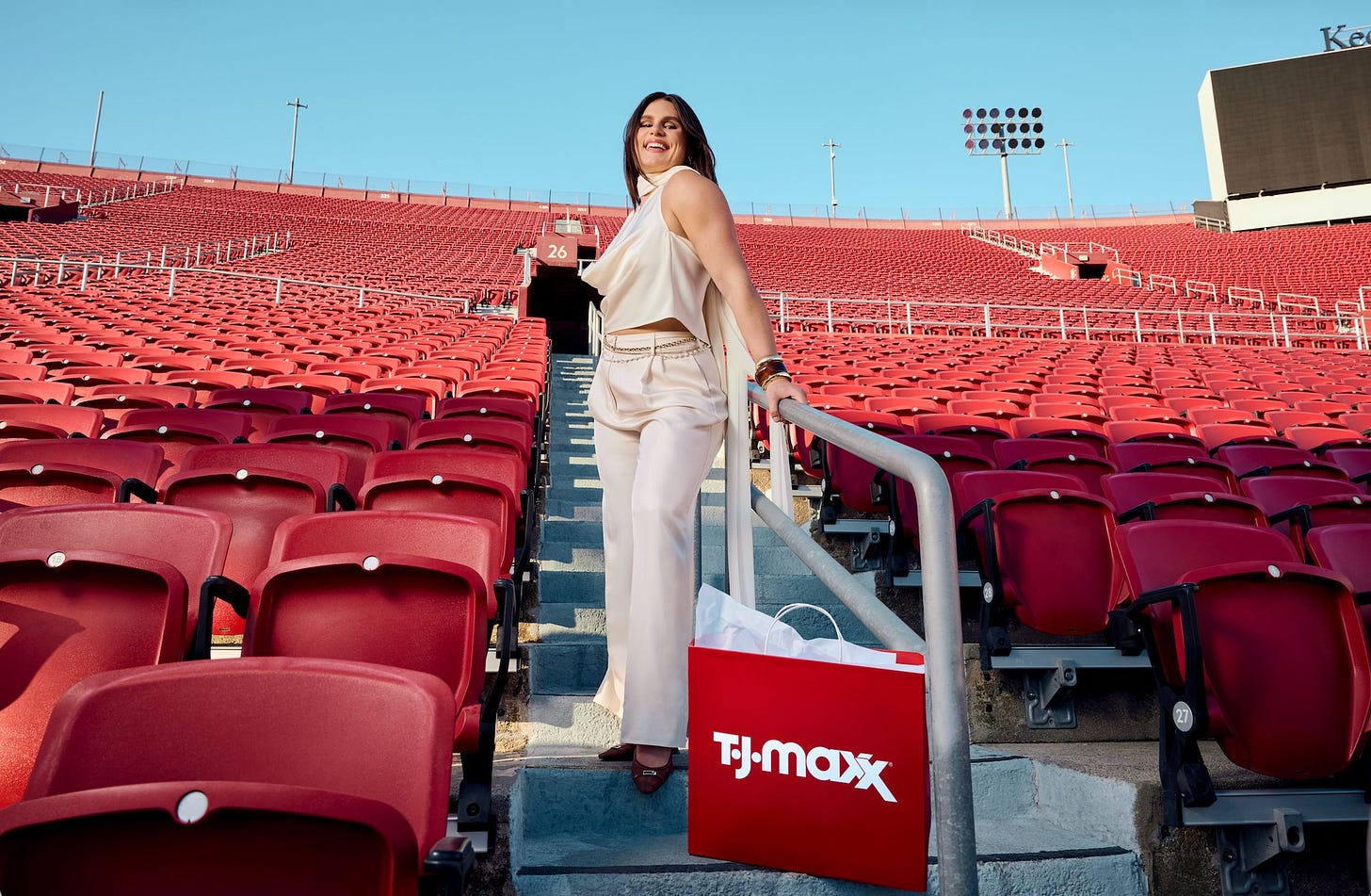 Ilona Maher standing among red bleachers with a TJ Maxx bag at her feet.