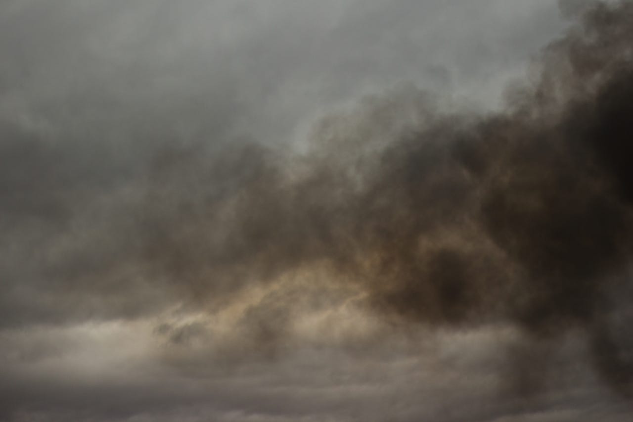 A photograph of a heavy, storm-laden sky filling the entire frame, with no ground or horizon visible. Photography by Joey Bania. A photograph of a heavy, storm-laden sky filling the entire frame, with no ground or horizon visible. Photography by Joey Bania.