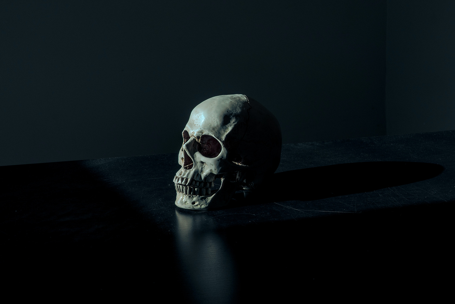 A skull sits on a surface against a black background. A skull sits on a surface against a black background.