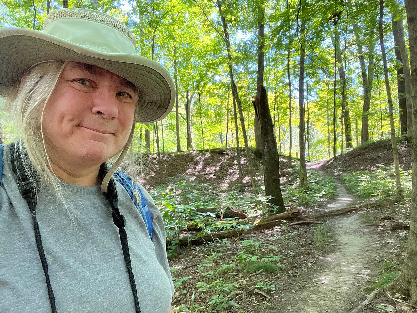 Woman on hiking trail in woods with trees atop an ancient levee