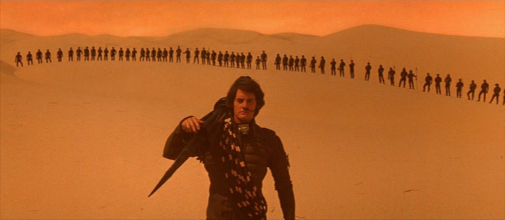 A person standing in a desert with a group of people in the background

Description automatically generated