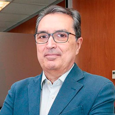 Homem de terno, óculos, e cabelos grisalhos curtos sorri levemente na foto Homem de terno, óculos, e cabelos grisalhos curtos sorri levemente na foto