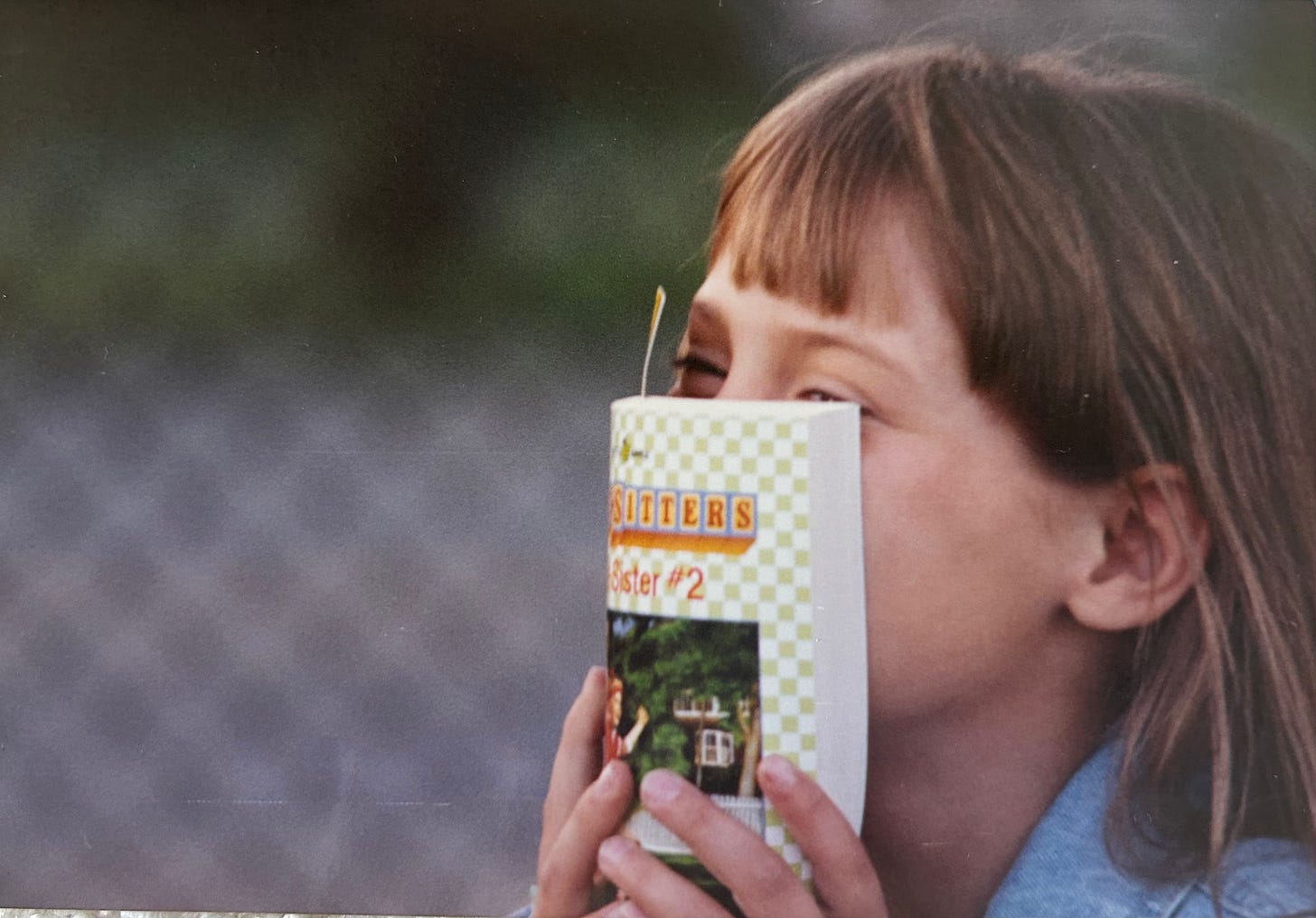 Image shows a picture of the author as a child, smiling from behind a novel