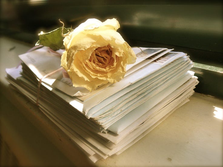This may contain: a stack of papers sitting on top of a table covered in a yellow rose flower This may contain: a stack of papers sitting on top of a table covered in a yellow rose flower