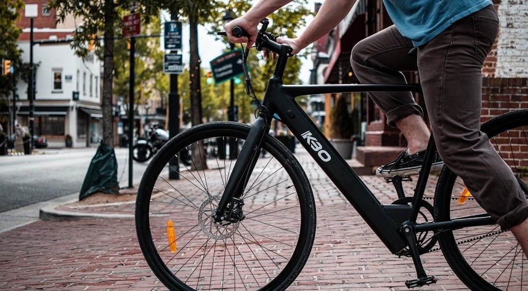 man in blue t-shirt and gray shorts riding black bicycle