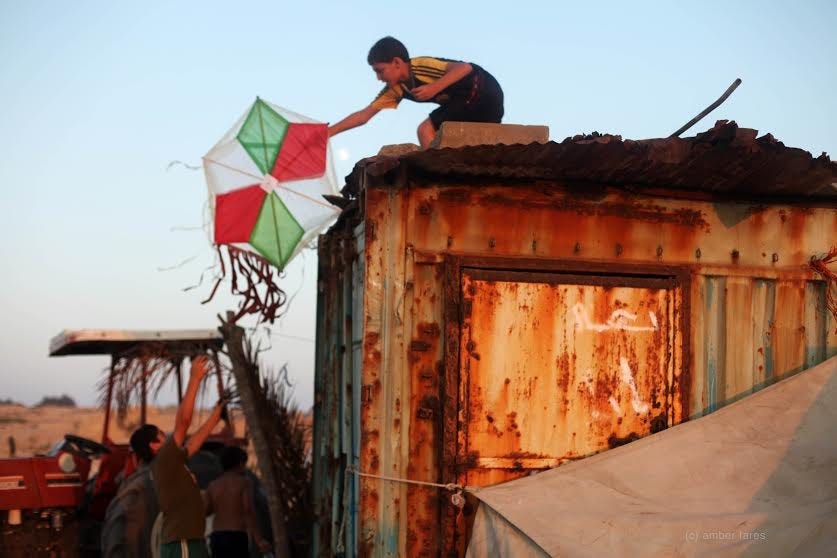 Musa fetching his kite from a roof while flying it on the beach in Gaza, during the filming of Flying  Paper in July 2010. (photo: Amber Fares)