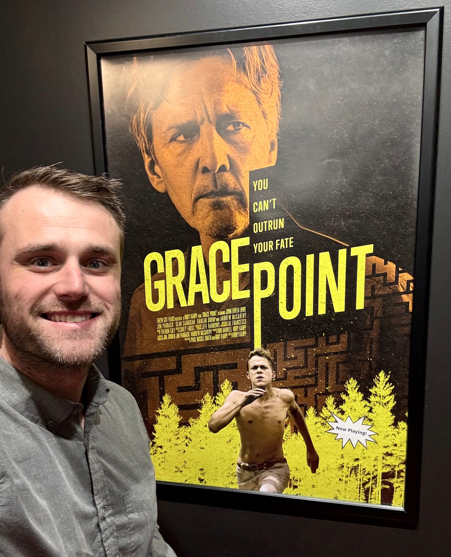 A man stands smiling in front ov a movie poster A man stands smiling in front ov a movie poster