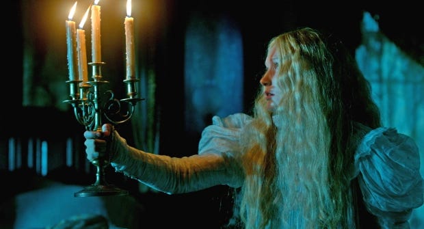 A woman holds a candle in a dark hallway