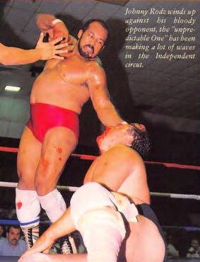 Johnny Rodz in red trunks raising his arm to throw a punch at a kneeling opponent in a wrestling ring, from a 1988 wrestling magazine
