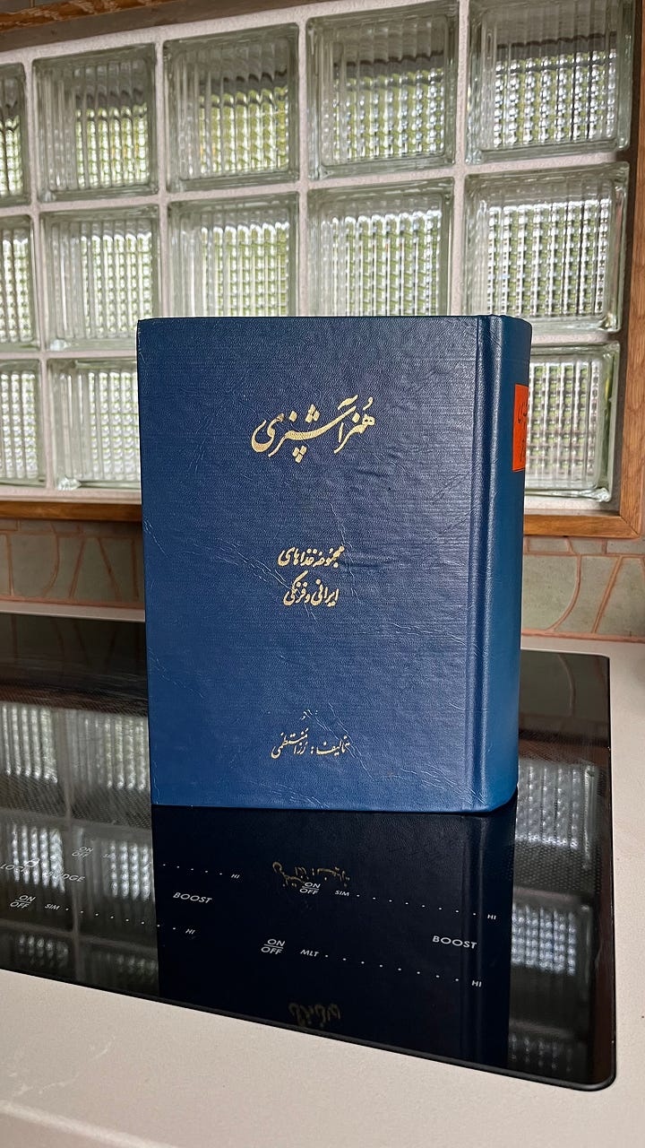 A blue cookbook with farsi writing in a kitchen and a Persian cookbook open to two pages.