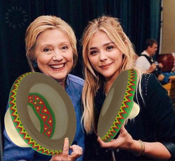 Hillary Clinton and Chloe Moretz smiling, each holding a colorful sombrero with red, green, and yellow zigzag patterns. They are indoors with a dark curtain and people in the background. A watermark from grandoldmemes is visible.